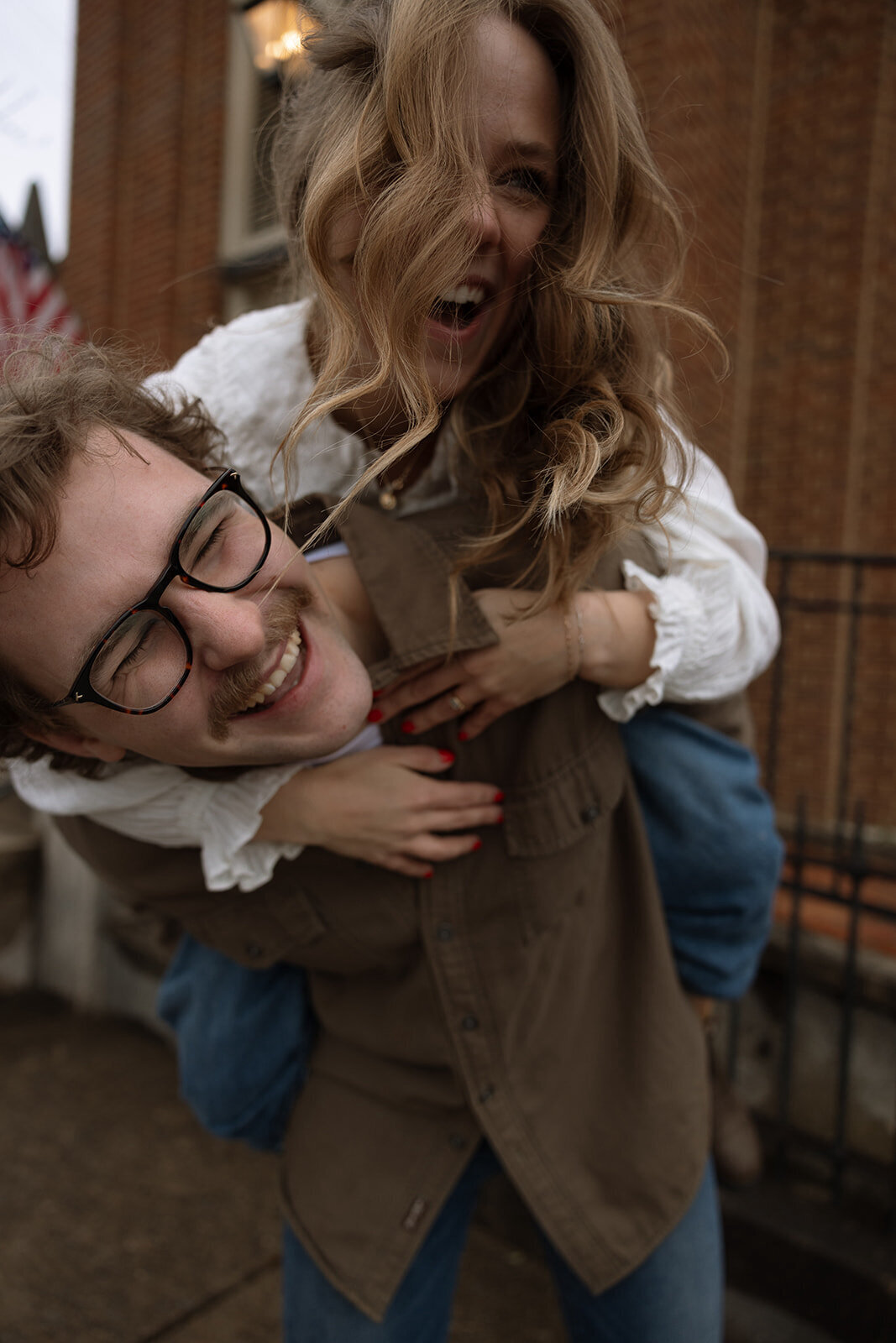 Candid couple enjoys shared laugh as groom gives bride a piggy back ride in Franklin, TN.