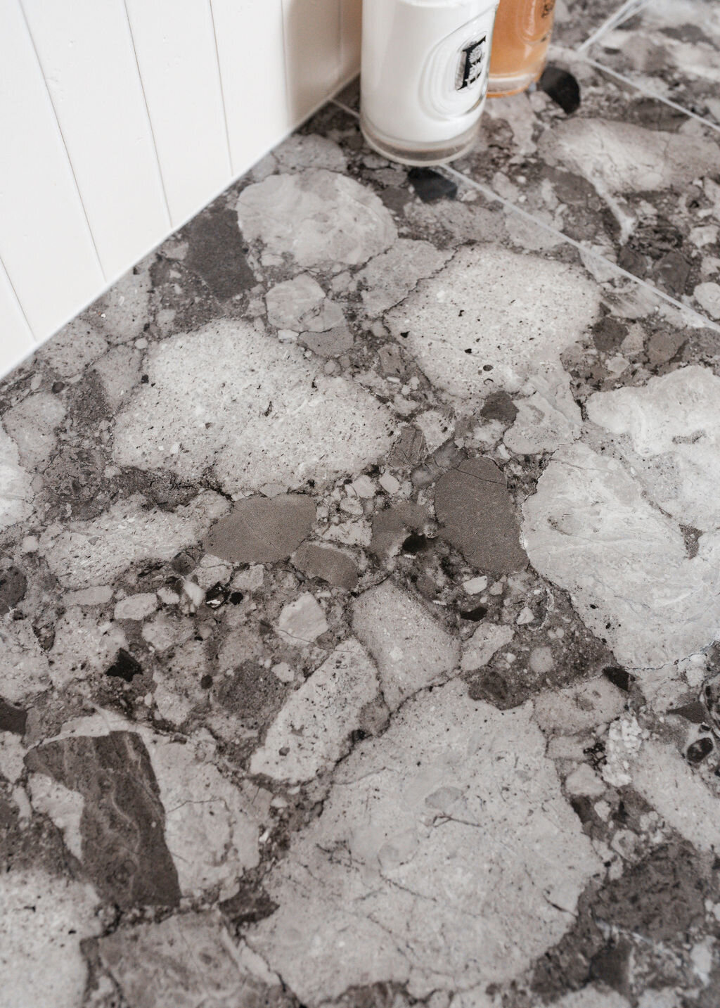 A close-up view of a grey marble bathroom vanity, showing the intricate black and white detail.