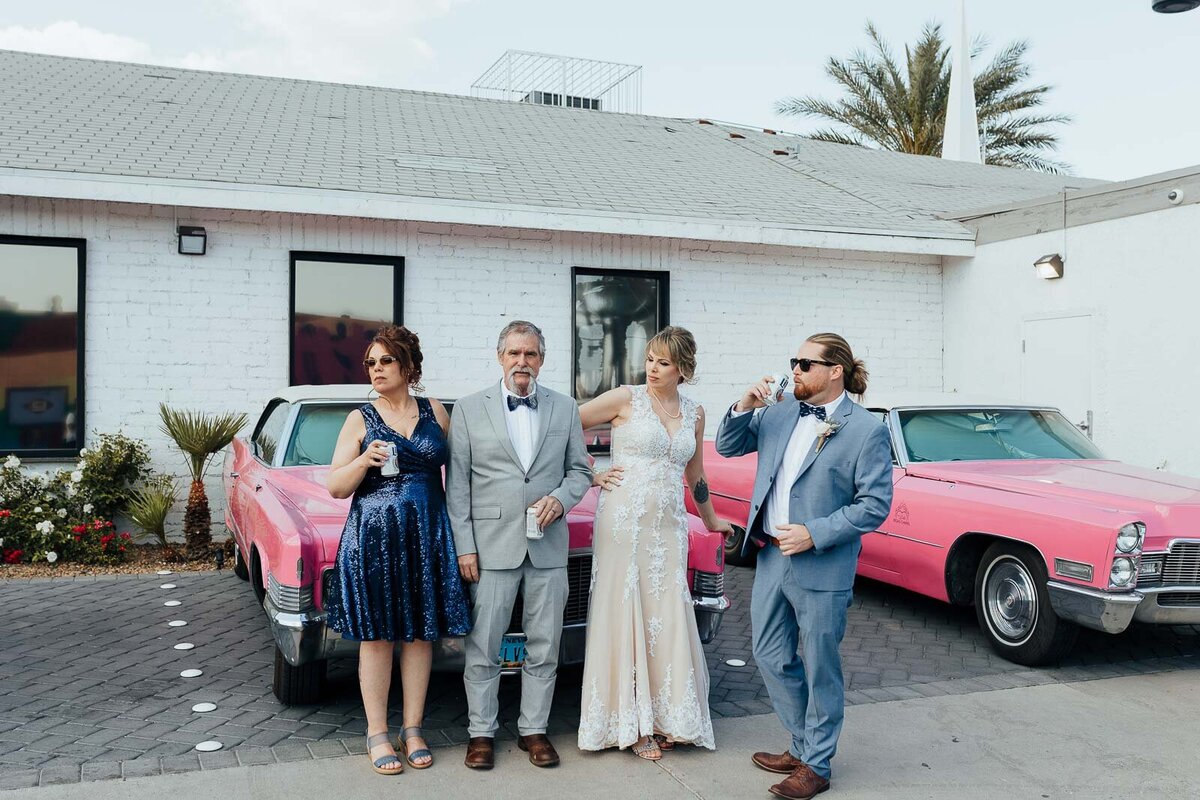 Family hanging in front of pink Cadillacs at chapel