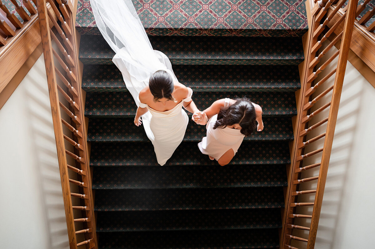 candid moment of bride with sister on staircase of southpointe golf club