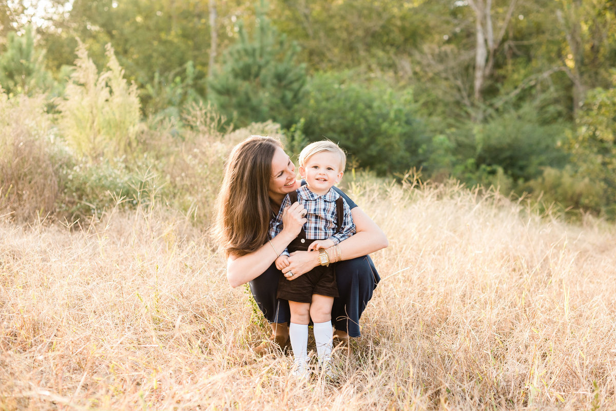 Mom pauses to play with her son at Horseshoe Nature Preserve for a Raleigh family photo session. Photographed by Raleigh NC Family Photographer A.J. Dunlap Photography.