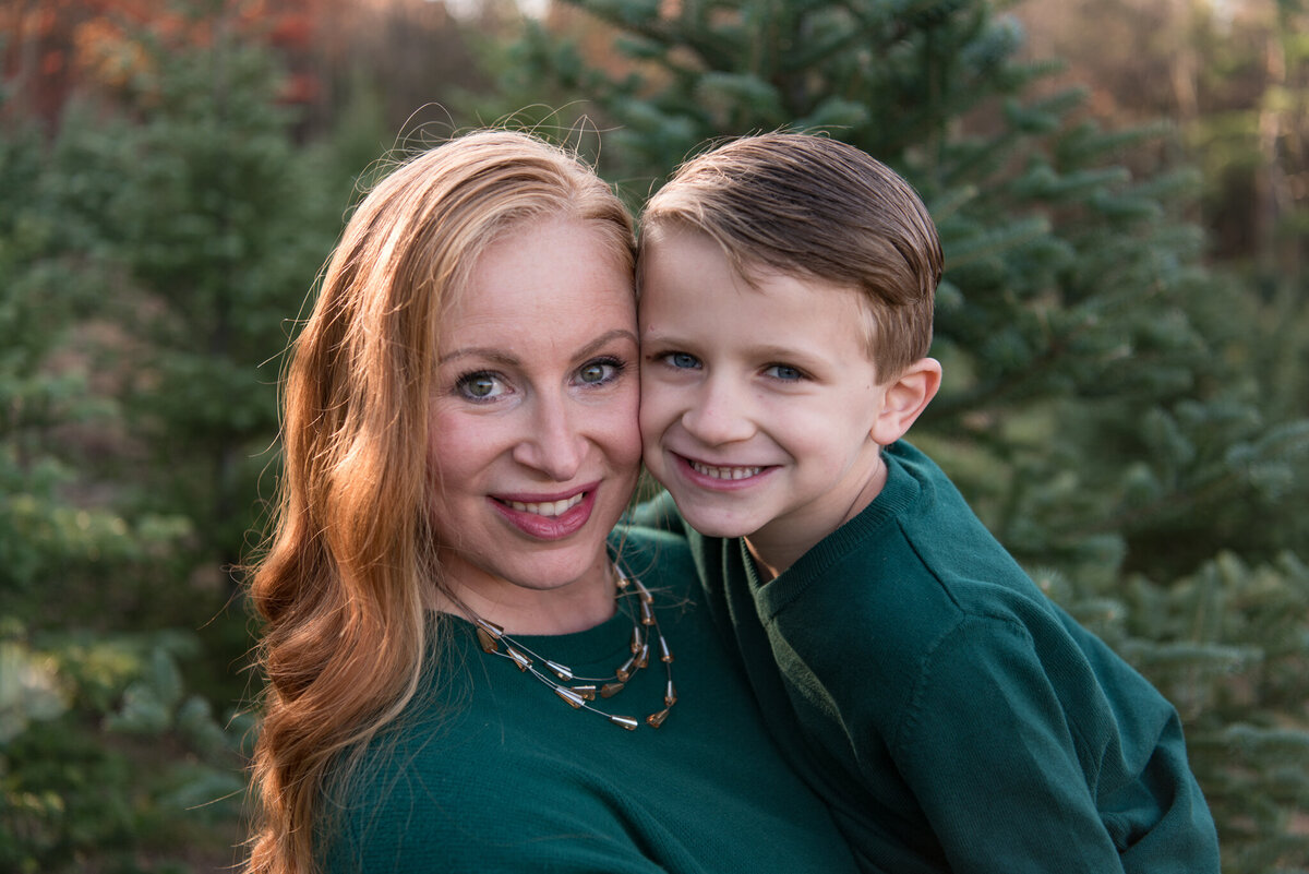 Mother and son smiling at camera at tree farm