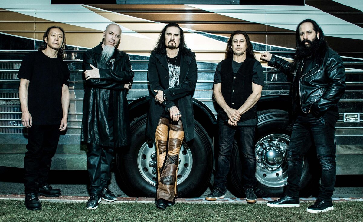 Musical group portrait Dream Theater leaning against tour bus