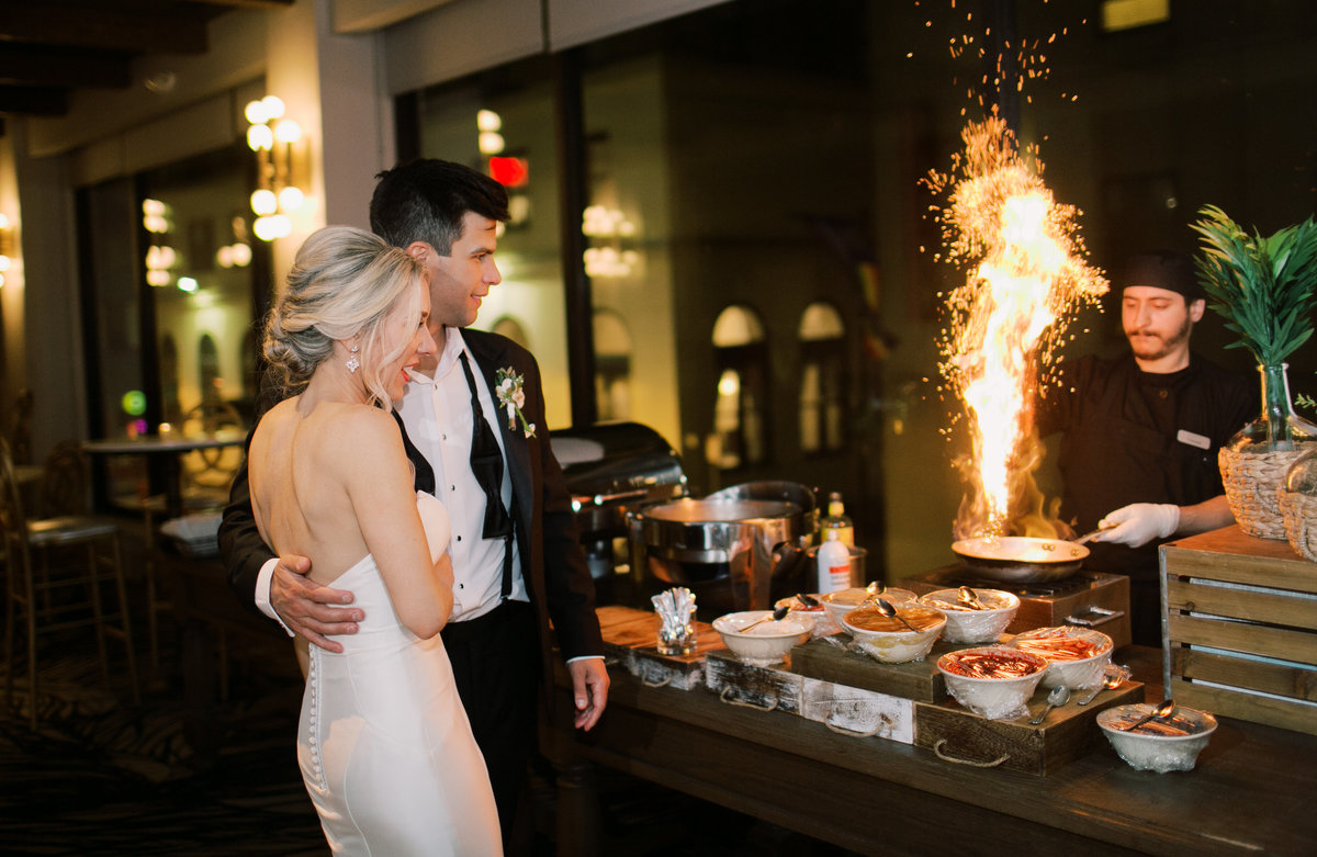 bride and groom watching chef cook at hibachi grill during wedding reception