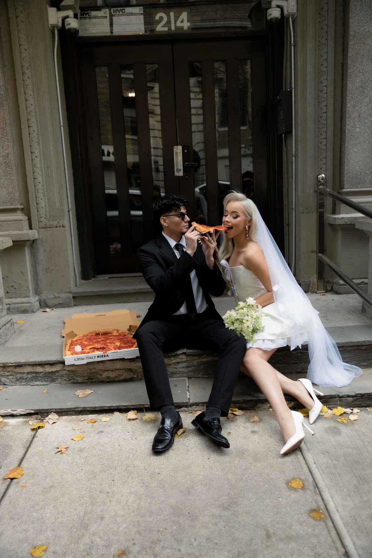 A creative shot of the pizza box open on a street corner in NYC, with the couple laughing in the distance.