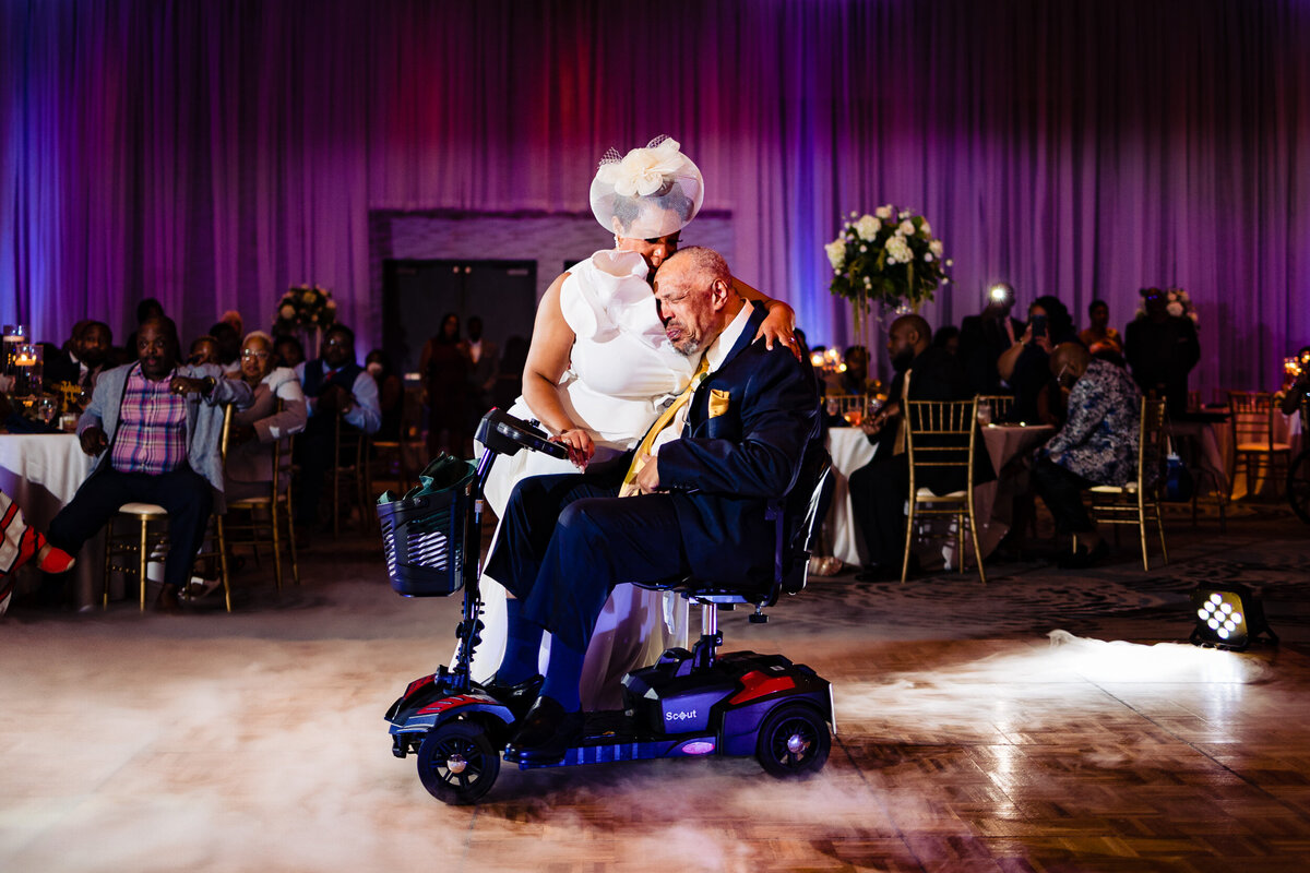 One of the top wedding photos of 2021. Taken by Adore Wedding Photography- Toledo, Ohio Wedding Photographers. This photo is of a bride dancing with her wheelchair bound father at the wedding reception. The two hug as the cry
