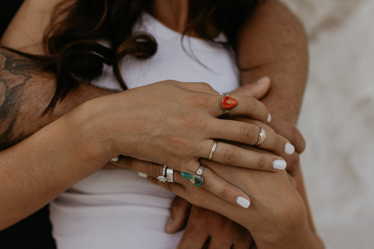 close up of a woman's hand with rings, holding her fiancé