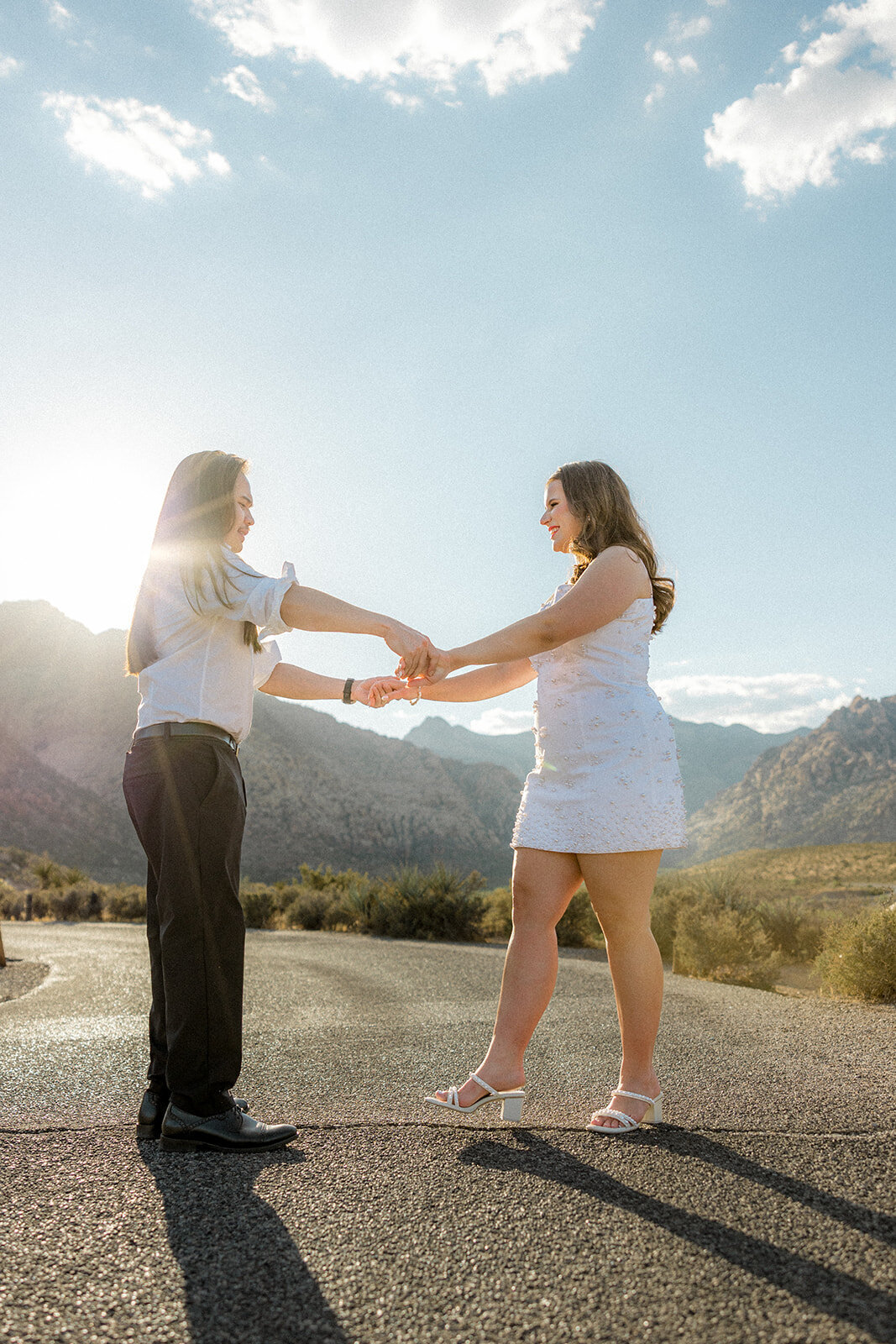 Engaged couple dancing on empty road with Nevada mountains in the back