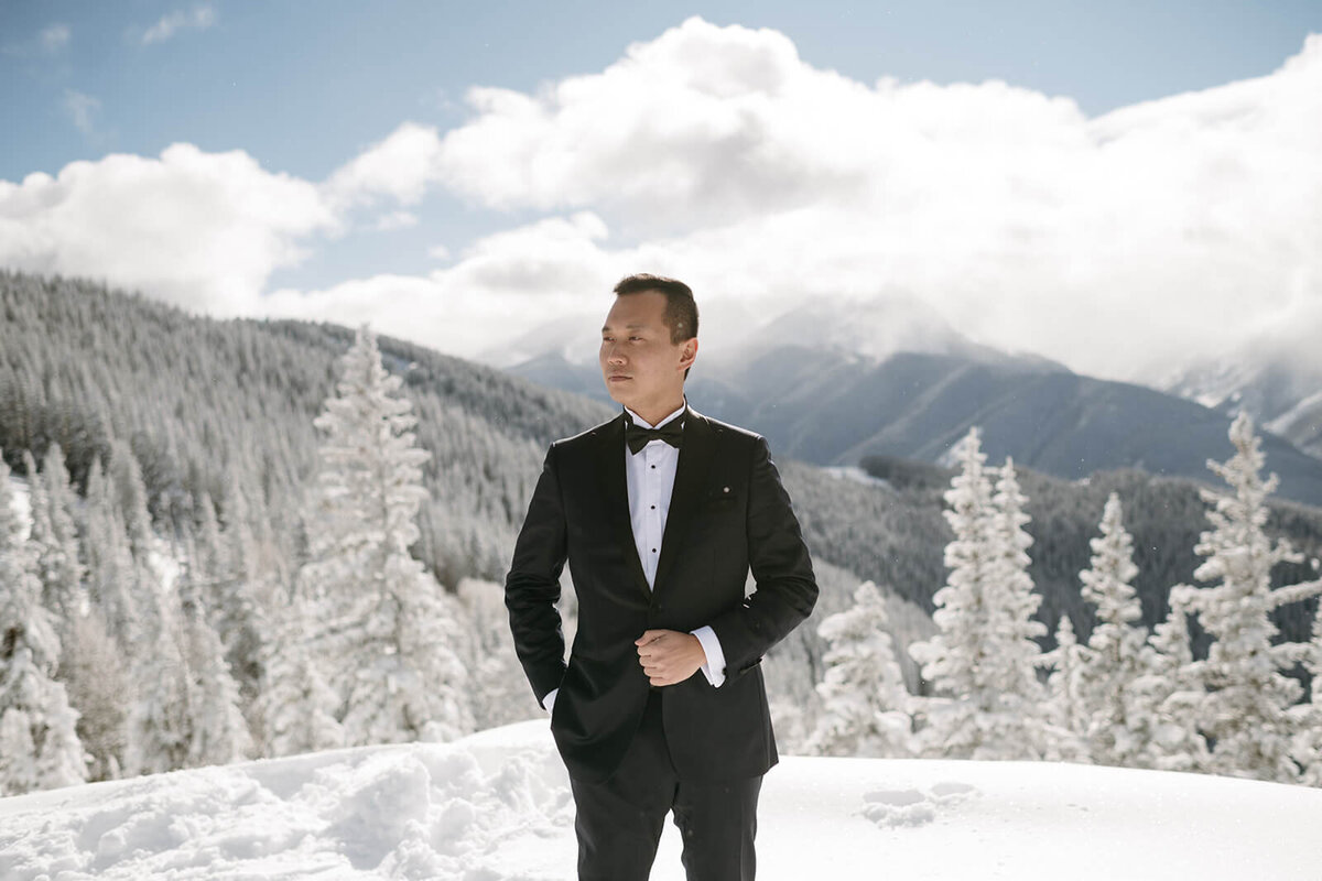 Groom standing on a mountaintop at St. Regis Aspen, with sweeping views of snow-capped peaks and a serene natural backdrop.
