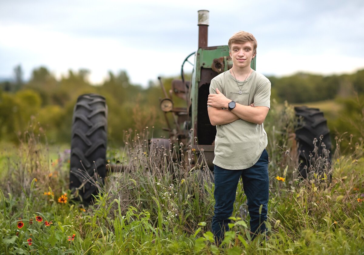 senior guy standing in front of tractor