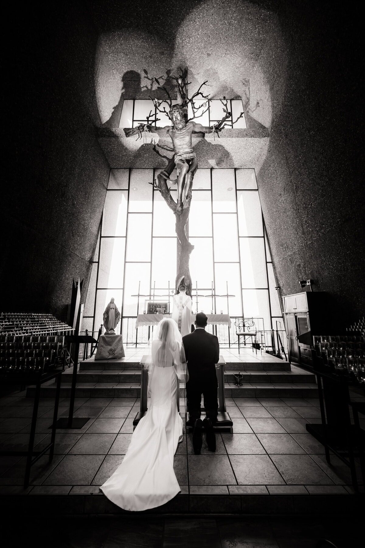 Bride and groom kneeling during ceremony at Chapel of Holy Cross