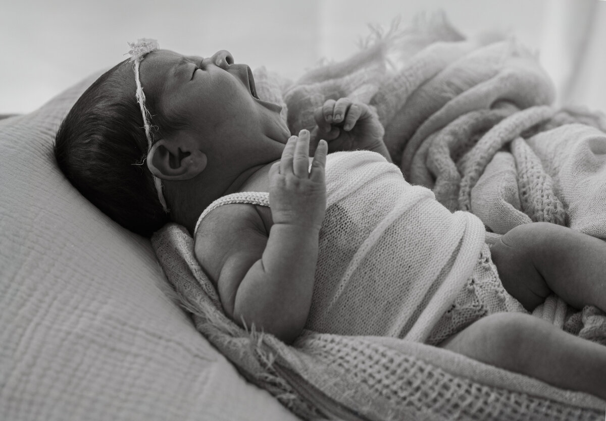 Geeuwende newborn baby op doek tijdens newborn fotoshoot