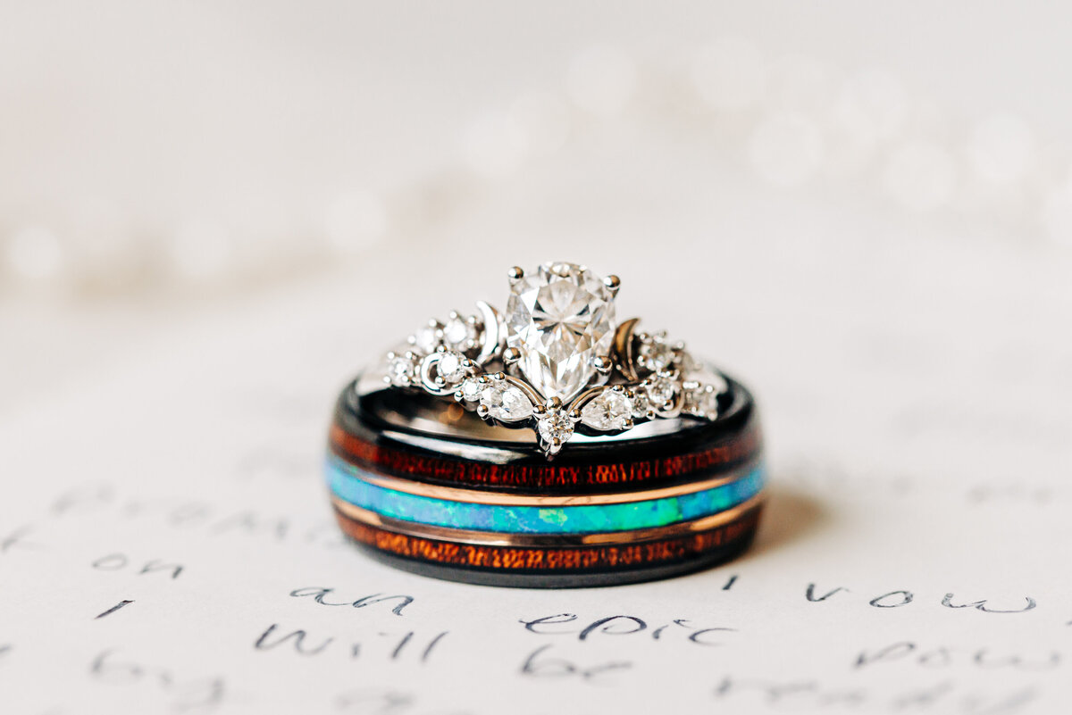 Close up photo of wedding rings sitting atop handwritten vow book