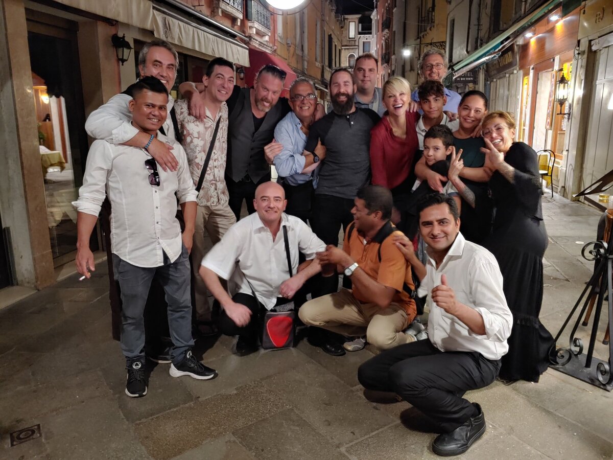 Employees and management of Ai Specchieri and Do Forni restaurants near Venice's St. Mark's Square gather with friends on street. 