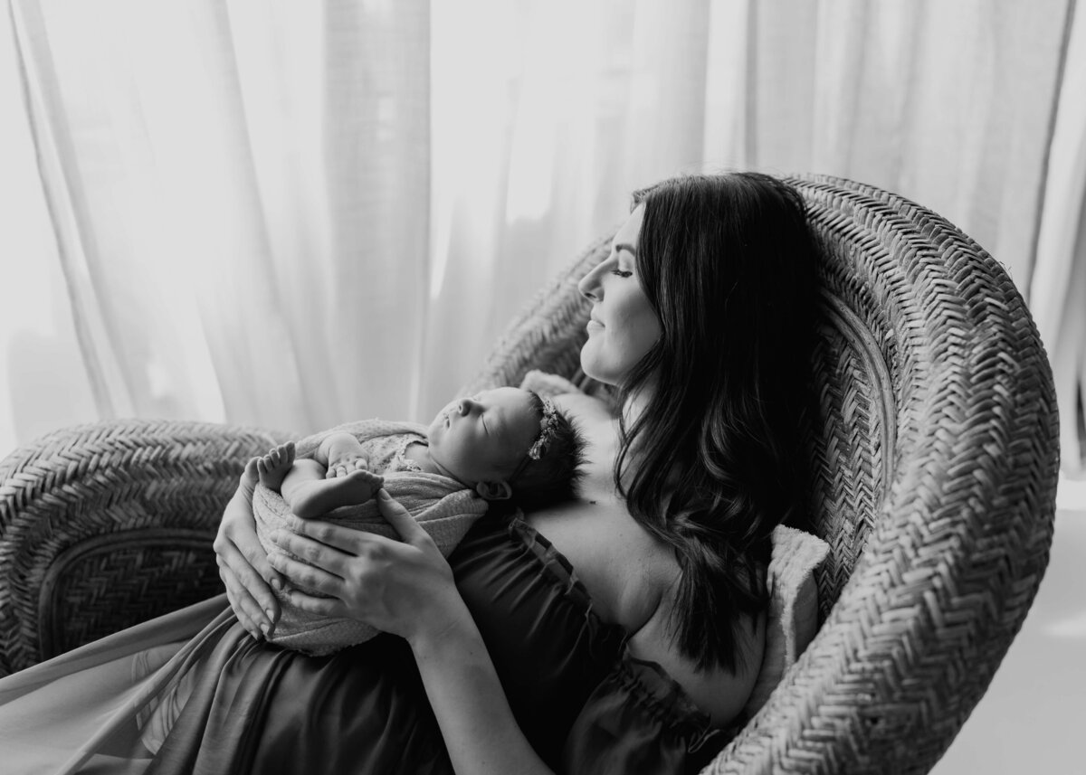 black and white of mother and new baby looking out large window