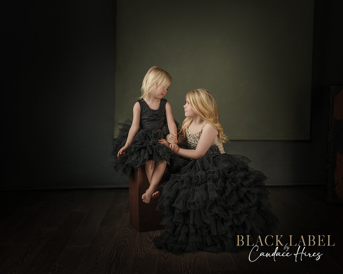 sisters photographed in tutu du monde gowns  on a black backdrop