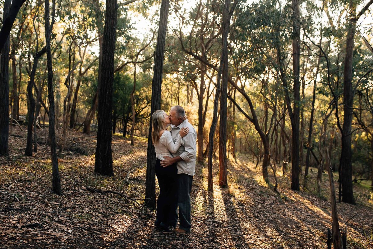 Older couple photography session Melbourne in bushland at sunset with couple kissing, And So I Don't Forget Photography