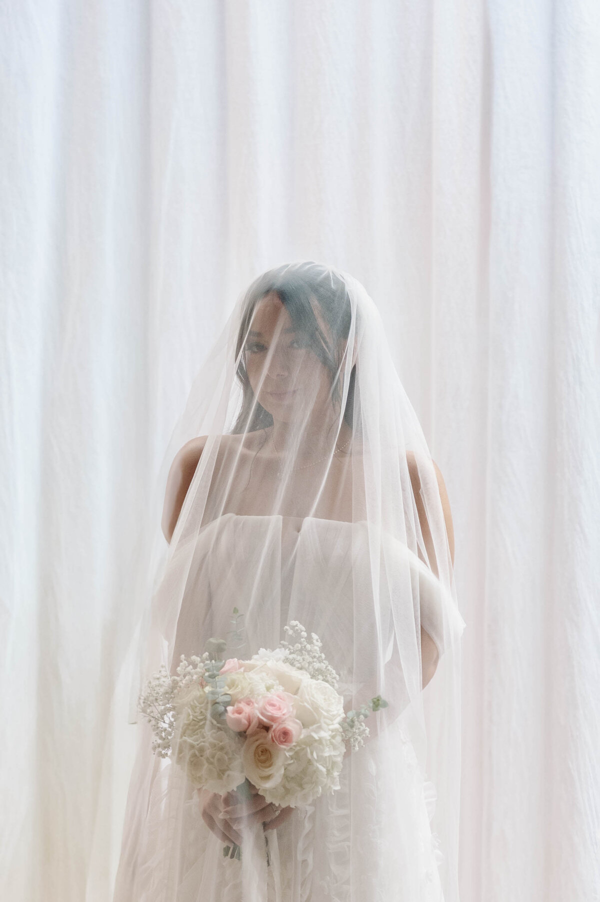 A bride poses in front of her bridal party, all wearing bright colors and holding white parasols.