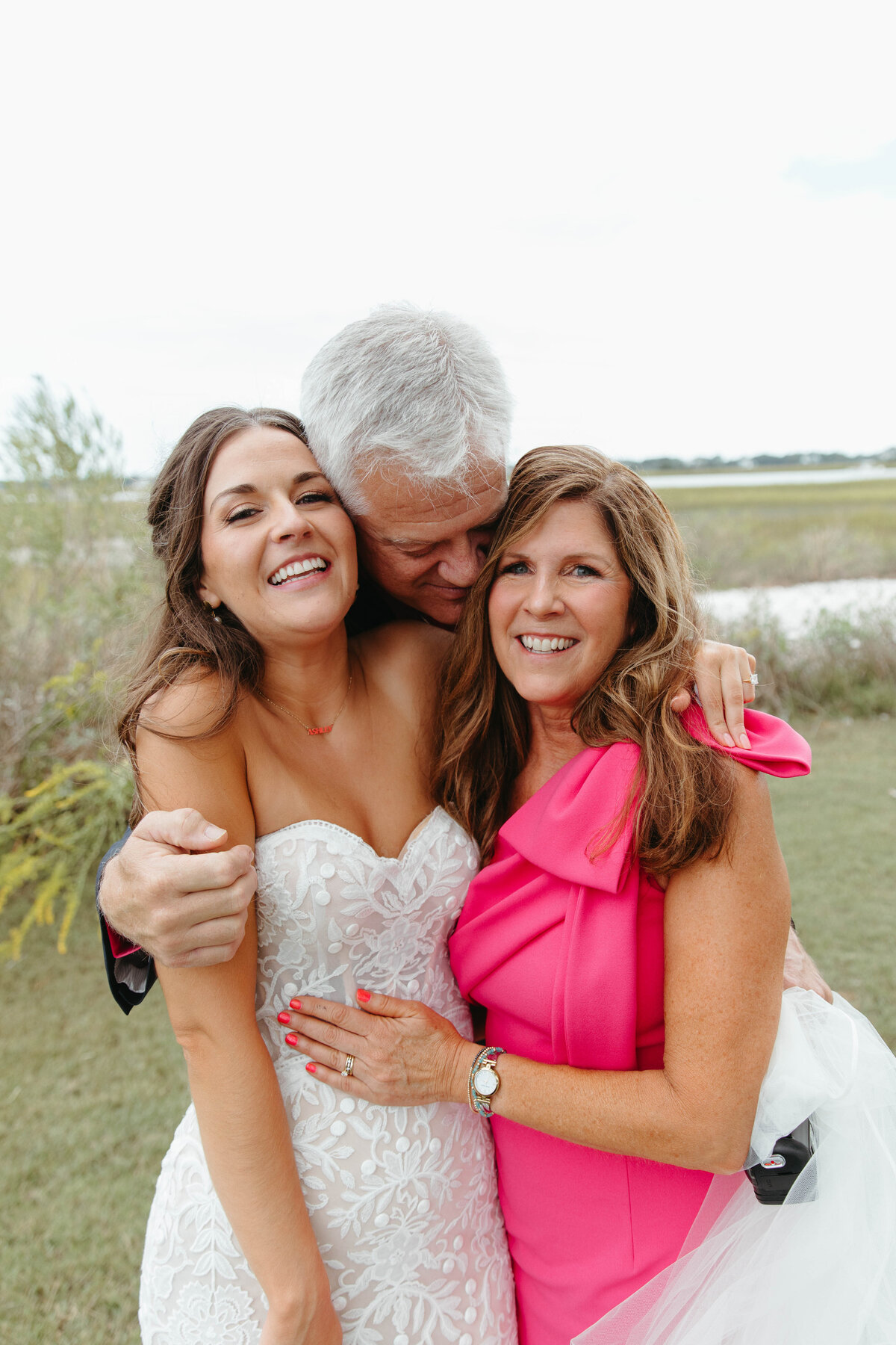 Bride being hugged by her mother and father
