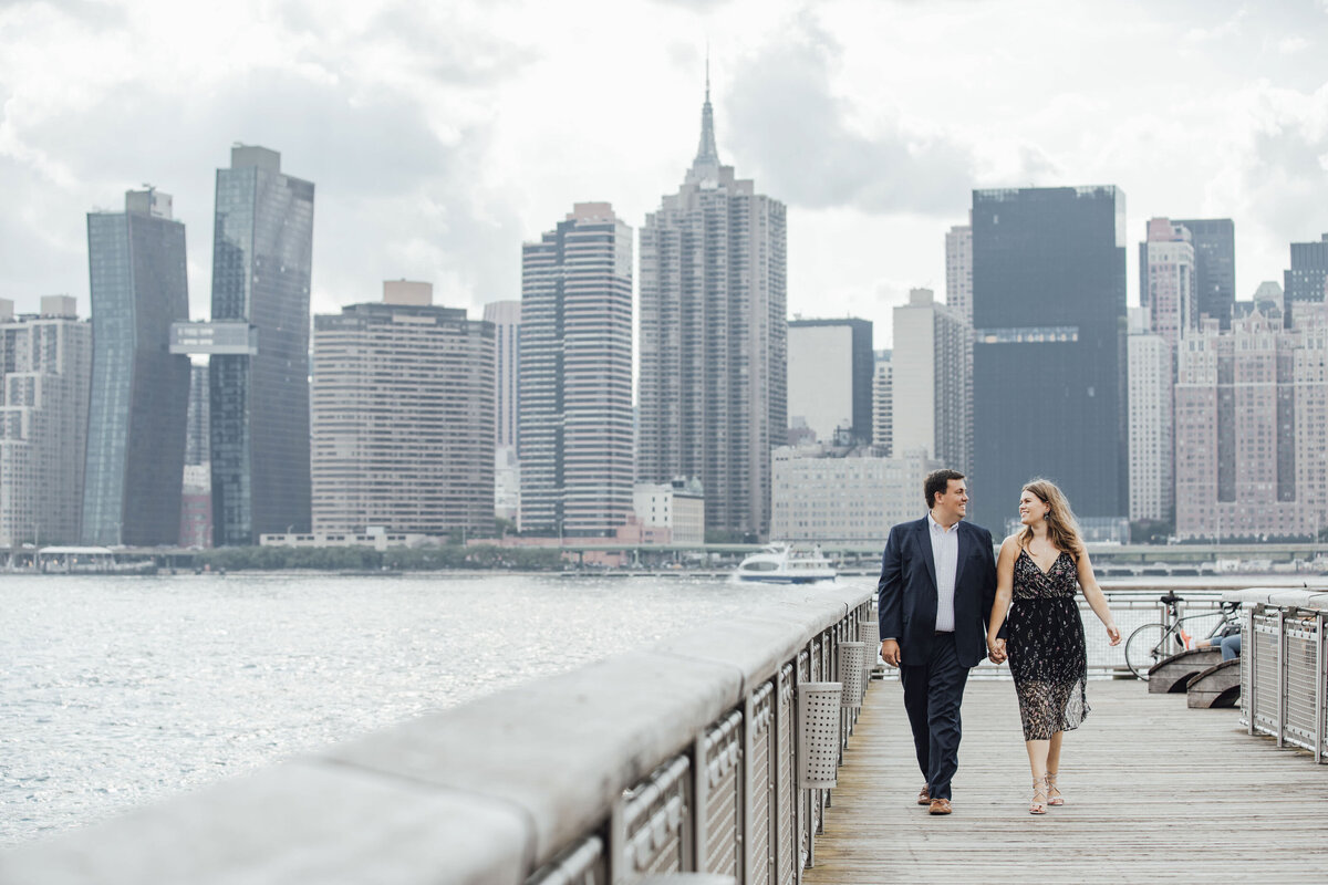 Couple on boardwalk with Hudson River skyline during engagement photo on Long Island New York