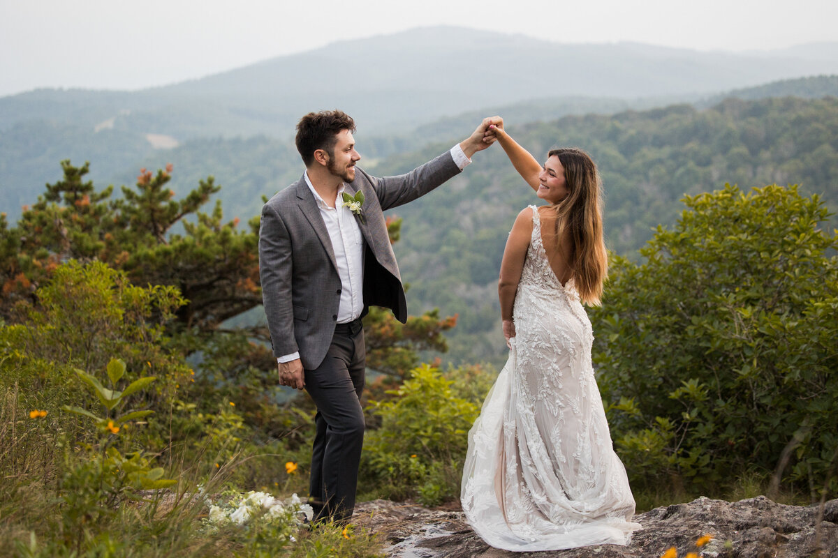 bride and groom dance in front of a mountain backdrop on the blue ridge parkway in nc
