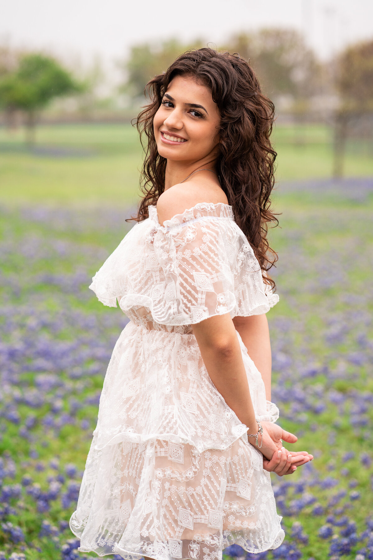 High School senior girl wearing white dress in bluebonnets. Austin Texas.