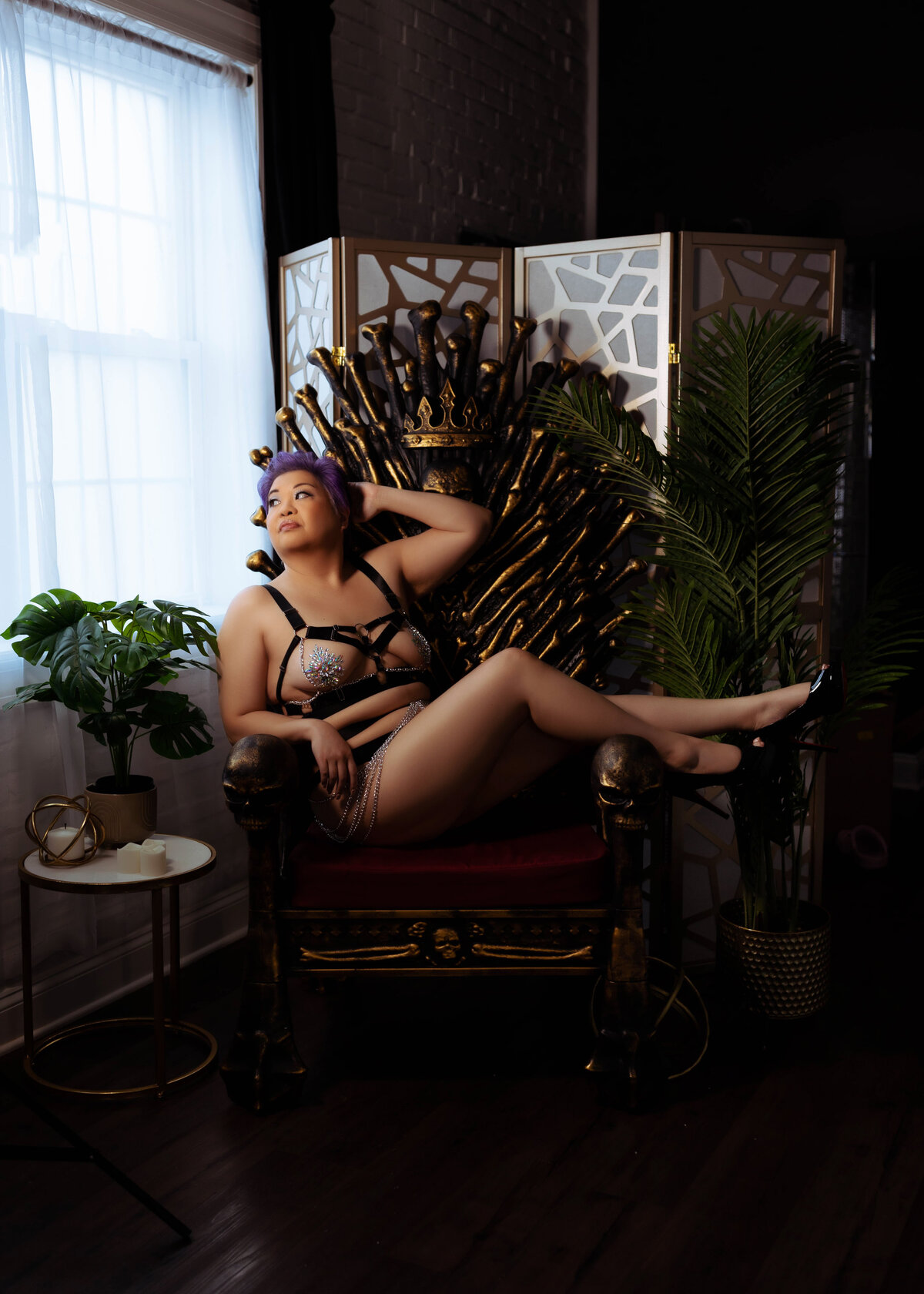 woman sitting and leaning in black lingerie in throne chair during boudoir session