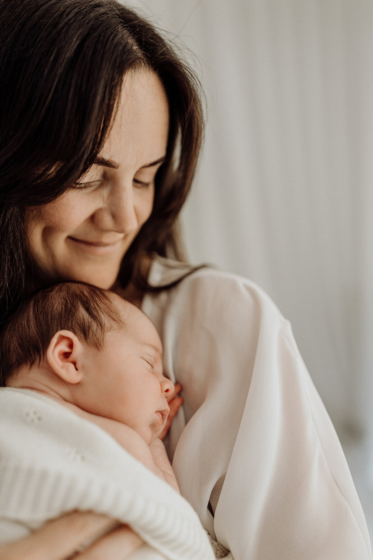 A mother wearing a maternity gown from the client wardrobe and holding a newborn baby during a christchurch newborn photoshoot