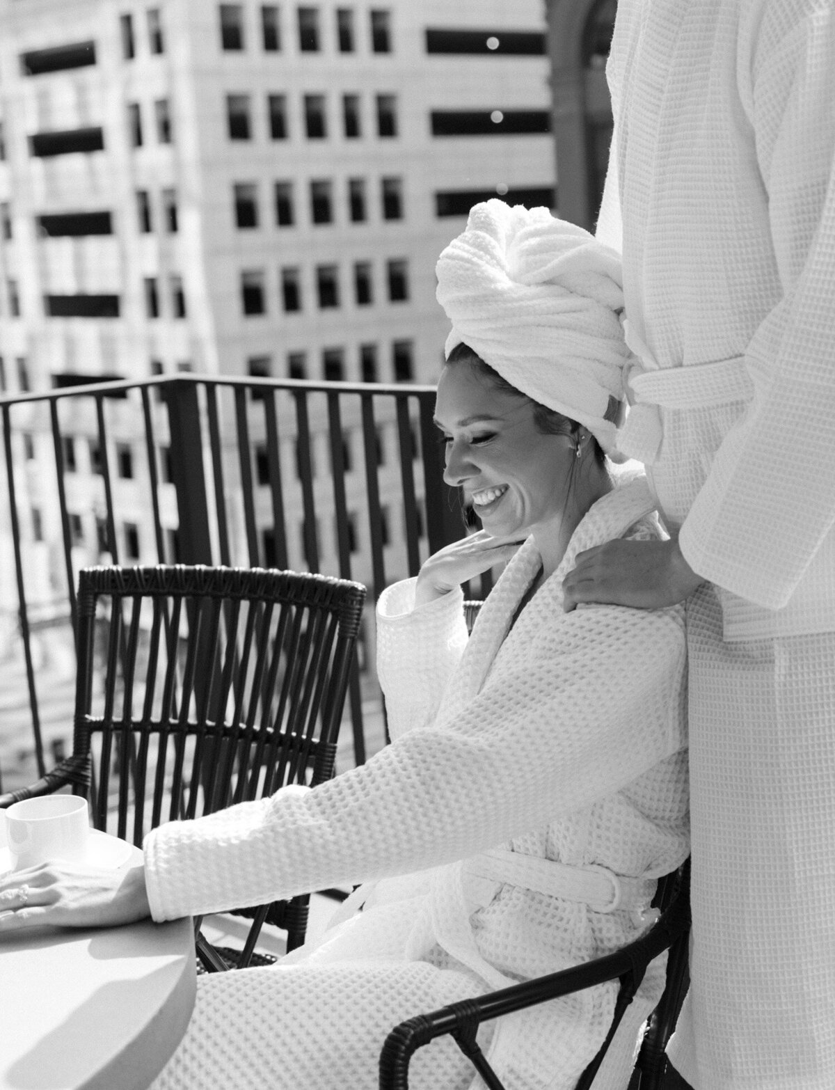 Woman in bathrobe and hair towel smiles with love on Shinola Hotel balcony in Detroit