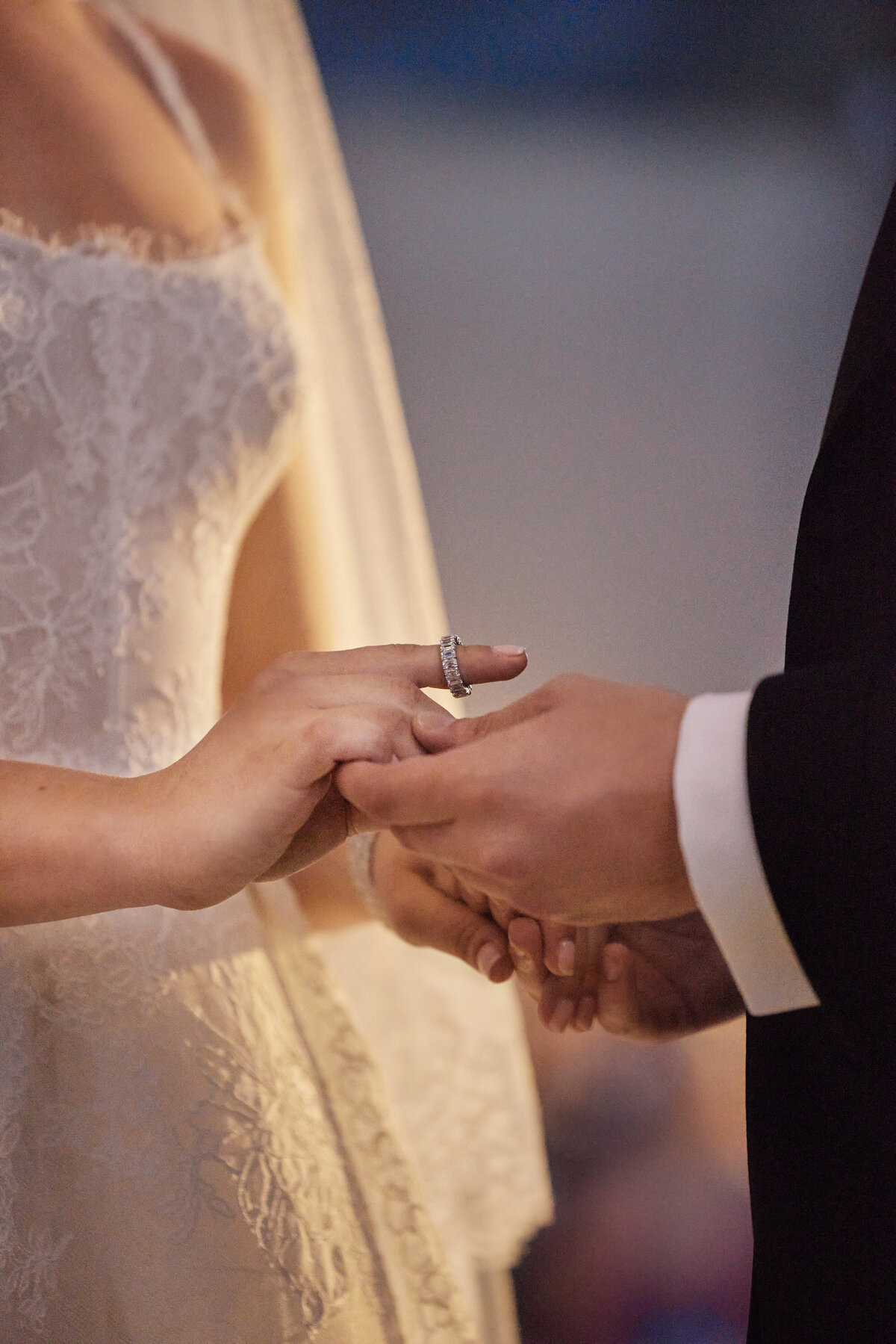 Bride and groom holding hands with ring on index finger