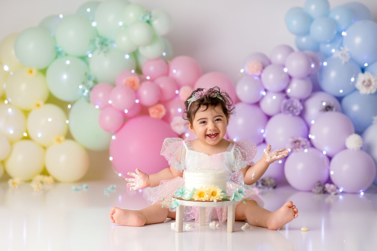 One year old Tampa baby enjoying a personalized luxury cake smash session with playful rainbow decorations