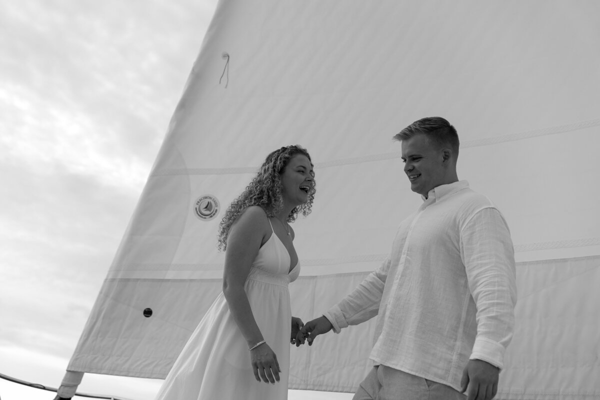Couple holding hands and laughing while sailing on a boat taken by Shelby Ann Photos, florida engagement photographers