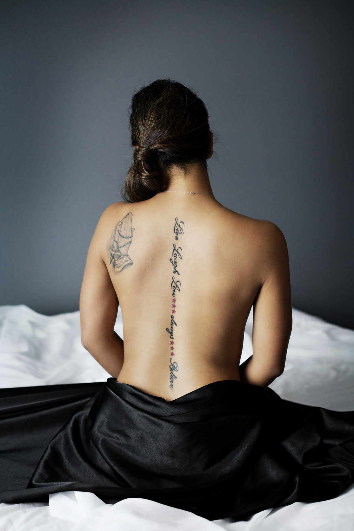 Woman with her naked back to camera shows off her tattoos