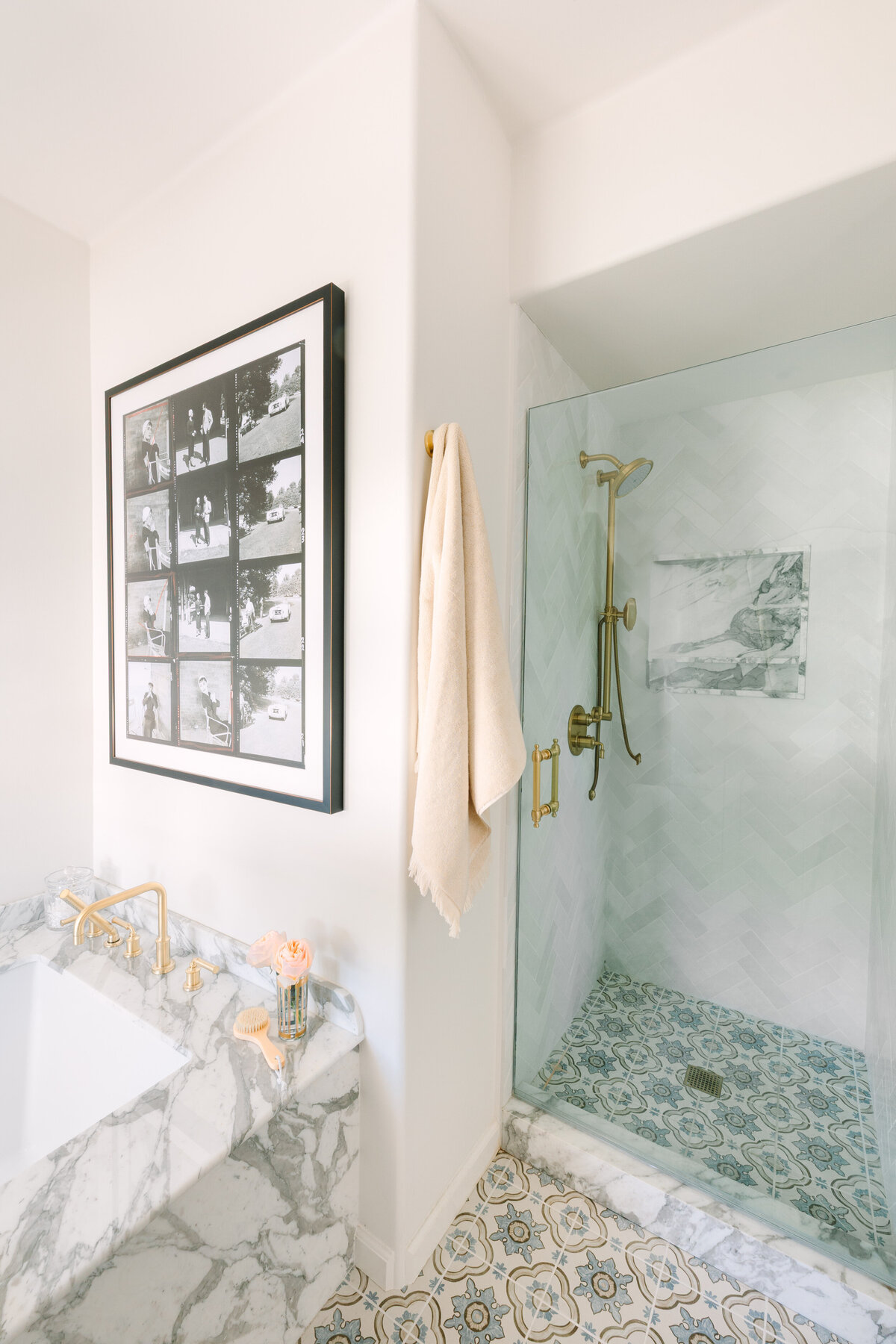 Primary bathroom with Chevron Chloe Tile, Arabescato Corchia marble niche, brass fixtures and patterned floor tile.