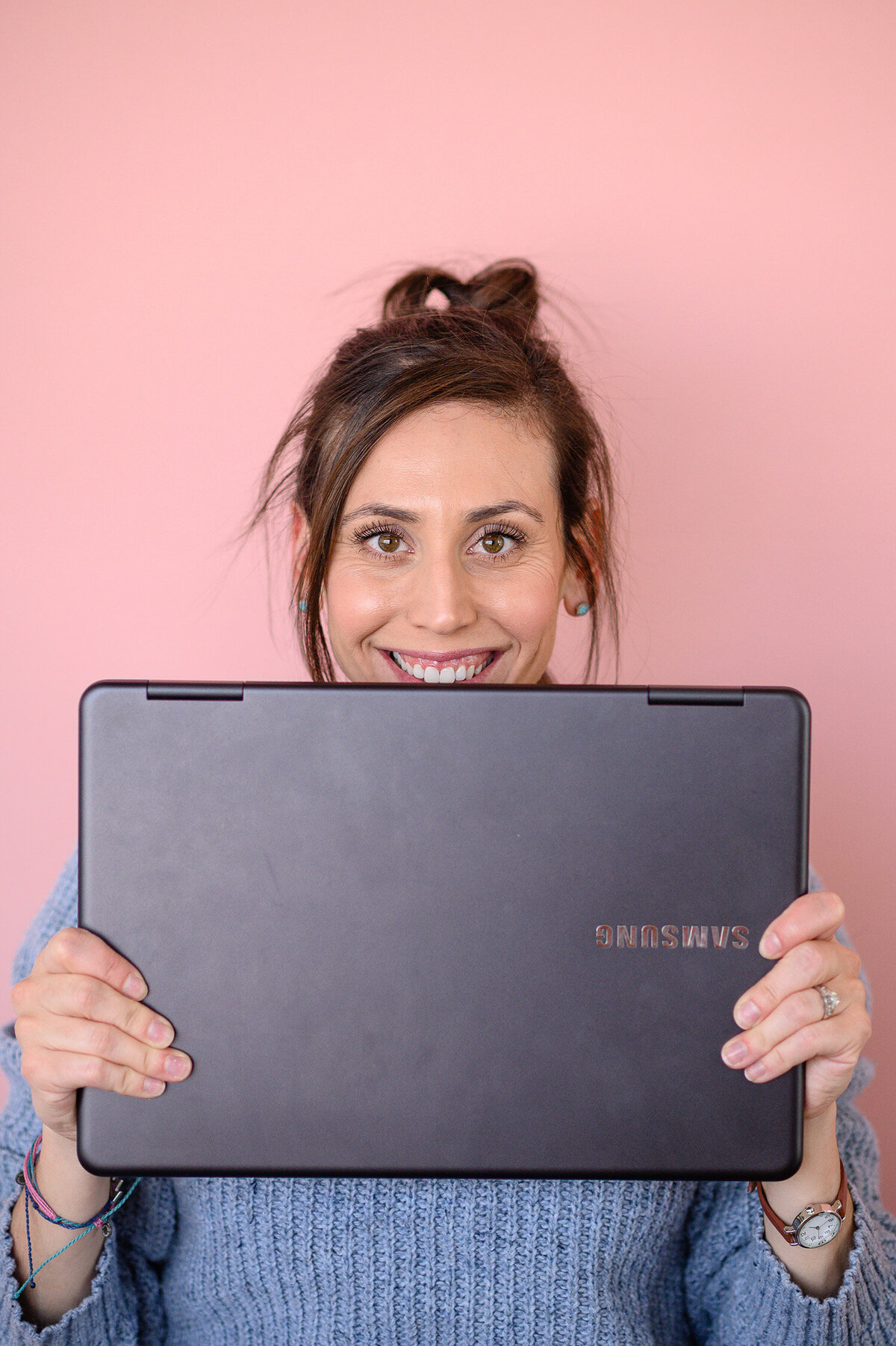denver commercial photographers pose woman business owner holding her computer in front of her face for branding photos