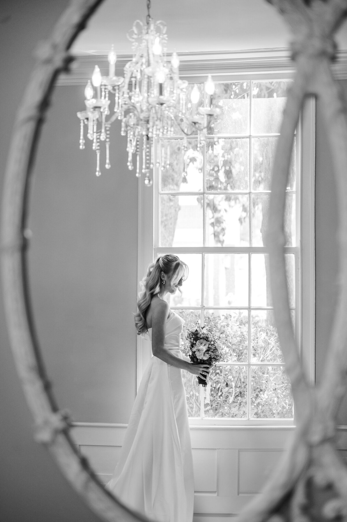 A stunning blonde bride during her bridal portrait session during the summer at The Leslie Alford Mims House in a black and white photo by JoLynn Photography, a Raleigh wedding photographer