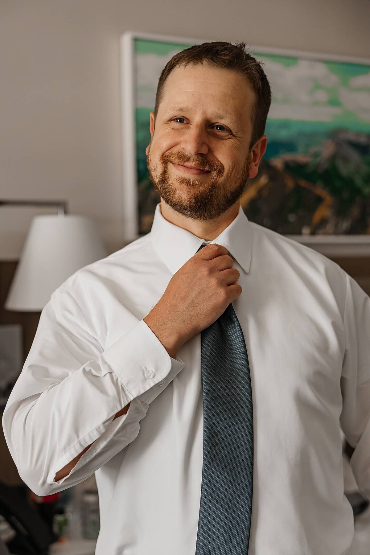 groom straightening up his tie and smiling on his Colorado Springs, Colorado wedding