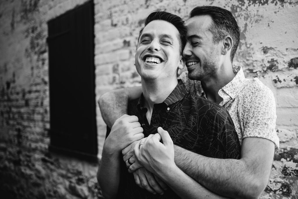 A person hugging their partner from behind as they both smile