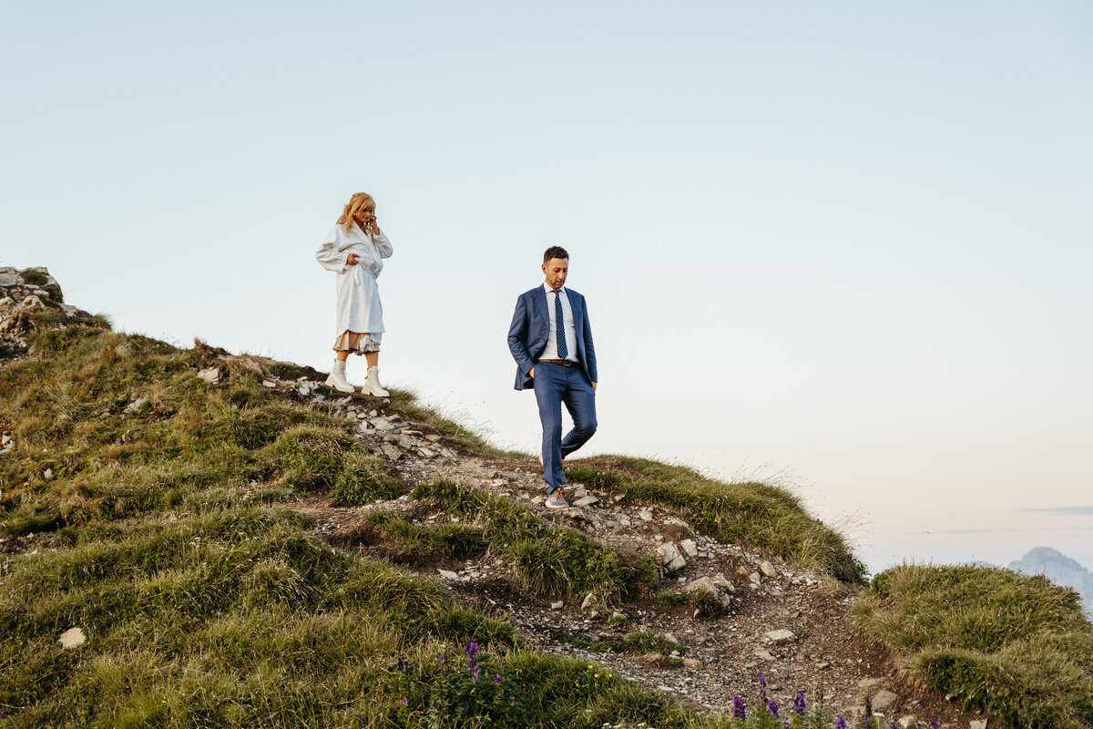 Bride and groom walking through mountain meadow golden hour
