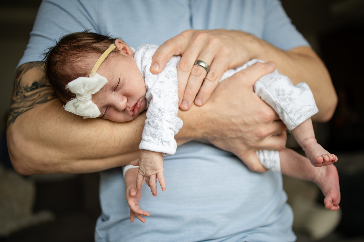 Baby girl sleeping laying across dad's arm