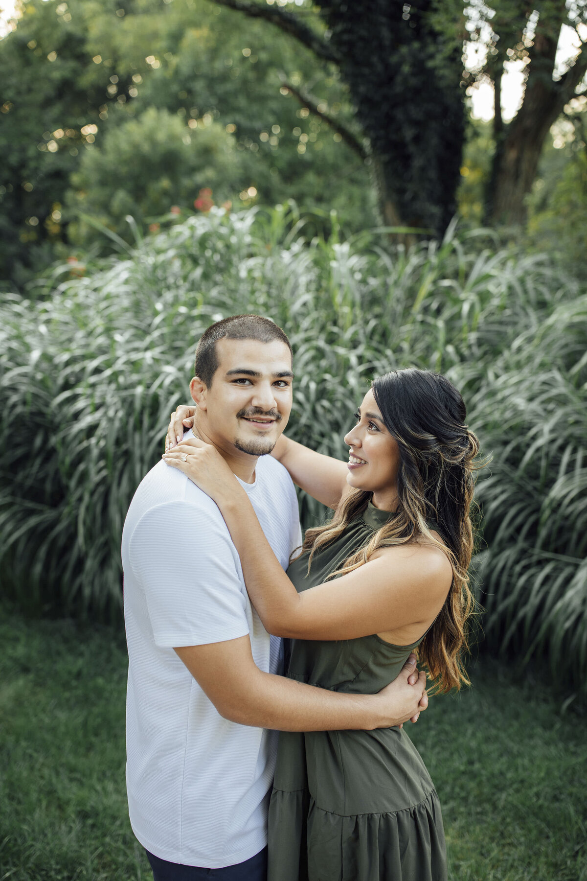 Couple hugging surrounded by greenery during spring engagement shoot at Sayen House and Gardens in Hamilton Township New Jersey