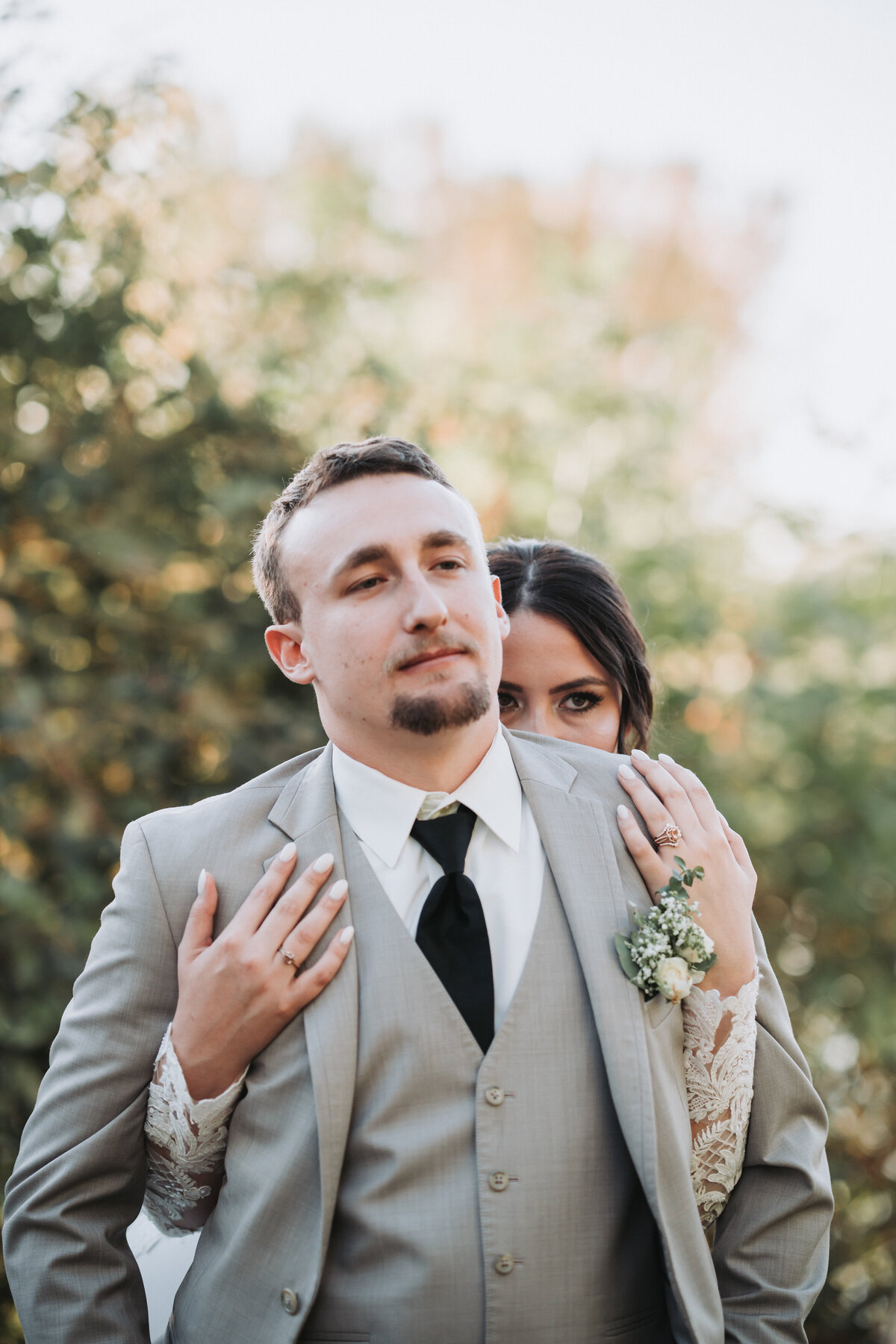 Groom and bride holding each other in a semi-serious attitude looking at the camera.
