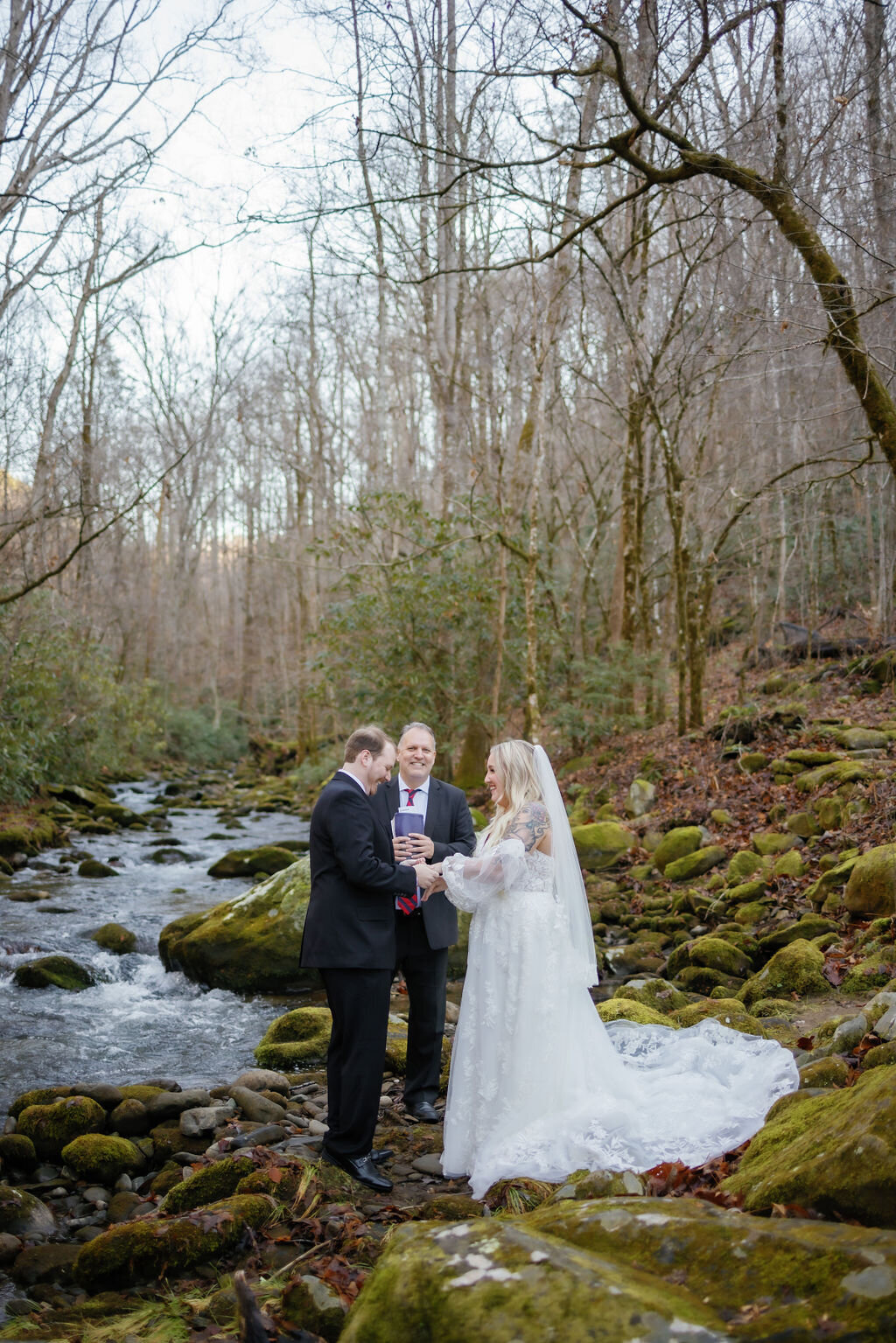 outdoor wedding ceremony with couple standing on river rocks covered in moss as they elope to Gatlinburg at Elys Mill 