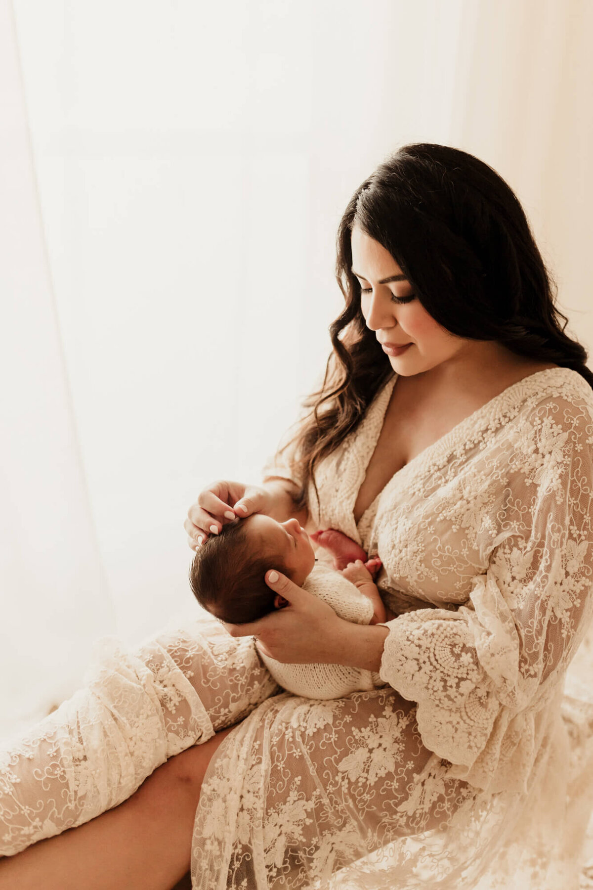 Mother looks down at her newborn baby boy, studio newborn session in OKC.