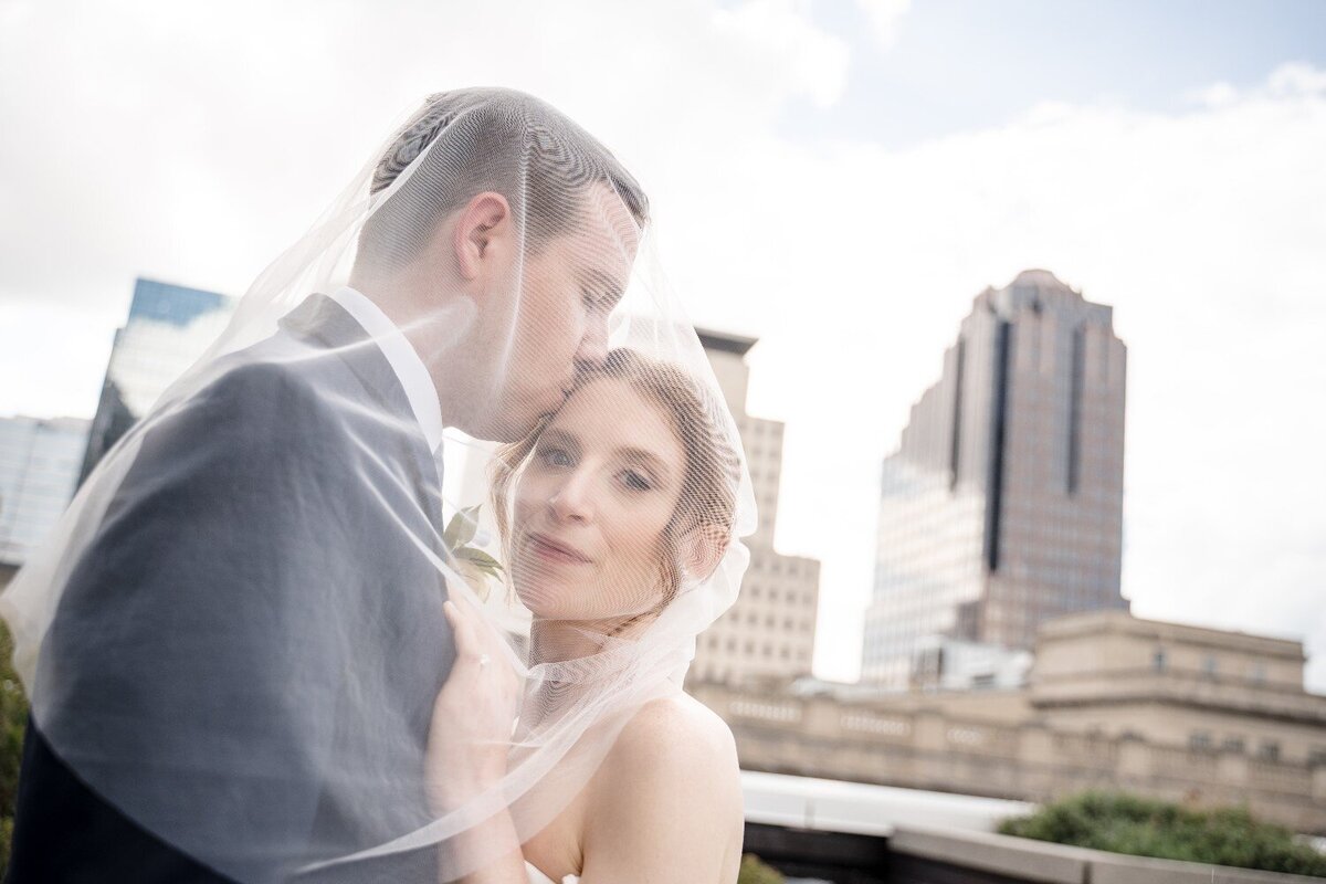 groom-kissing-bride-forehead-wedding-rooftop-indianapolis-jps-events.jpg