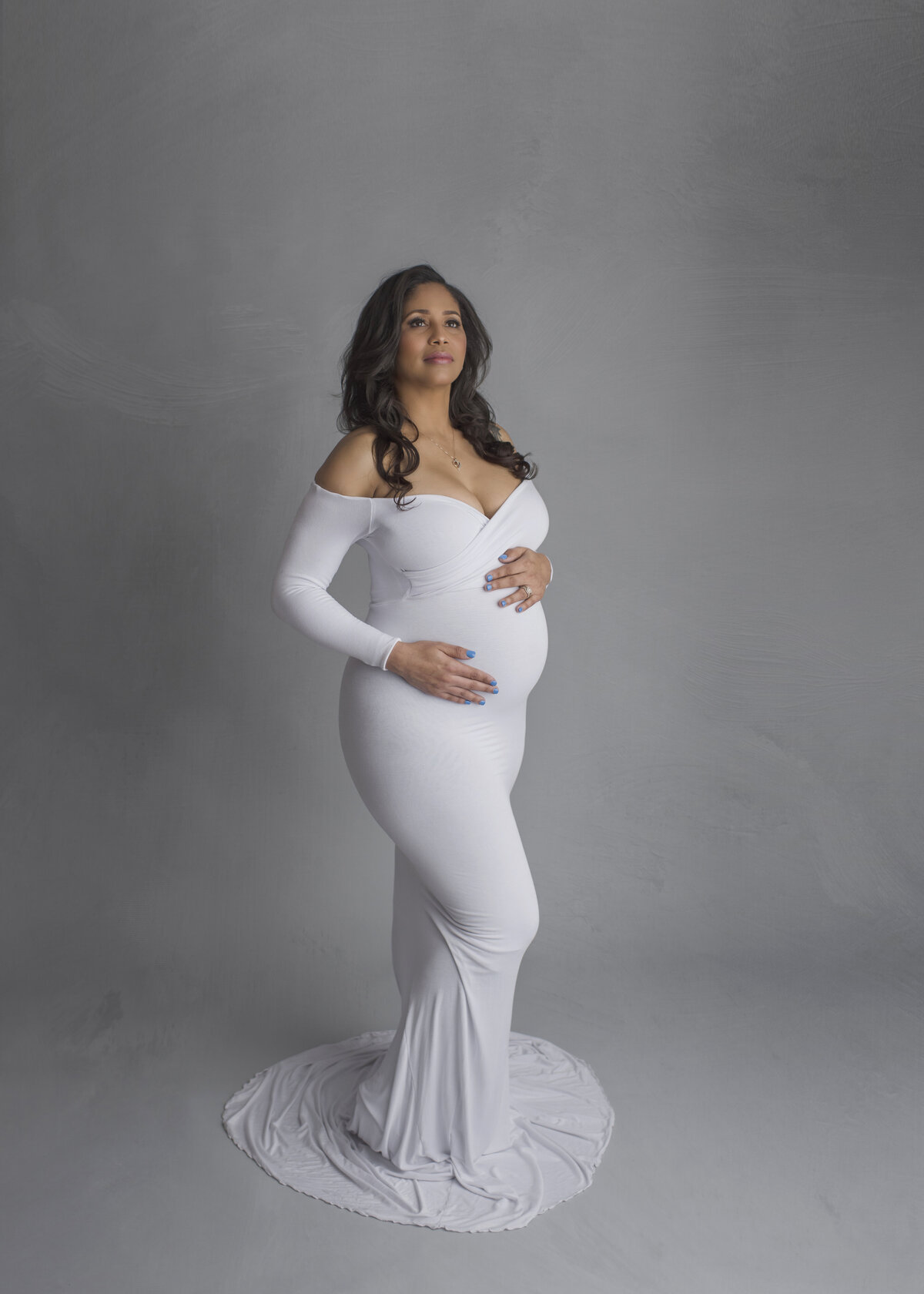 inside studio maternity session of lady in white dress matching background