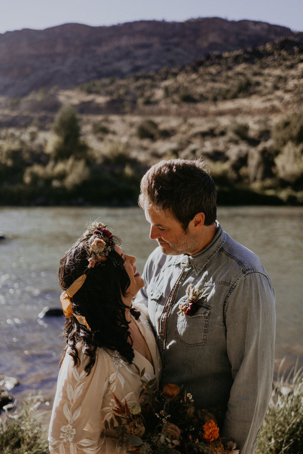 bride and groom holding each other in front of the Rio Grade in Taos, New Mexico