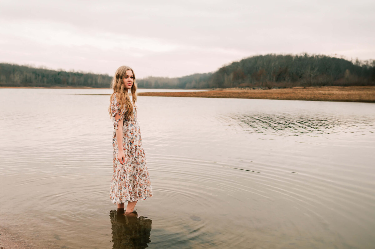 senior pictures in Branson fo high school senior standing in lake on a gloomy day