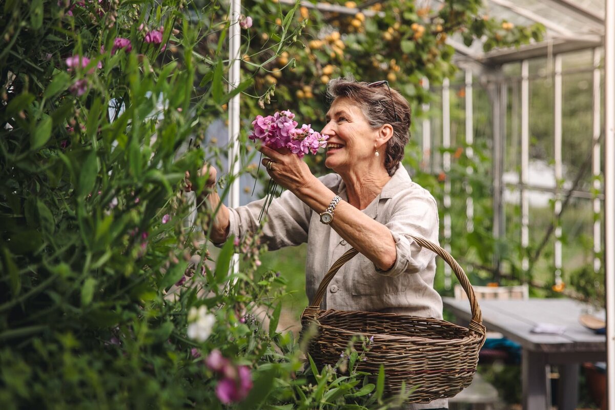 Porträtt av värdinna i pensionatets trädgård – verksamhetsfotografering som fångar känslan av småskaligt och genuint.