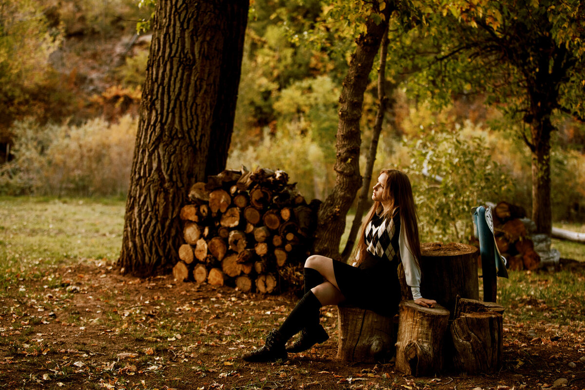 girl sits on a wooden stump